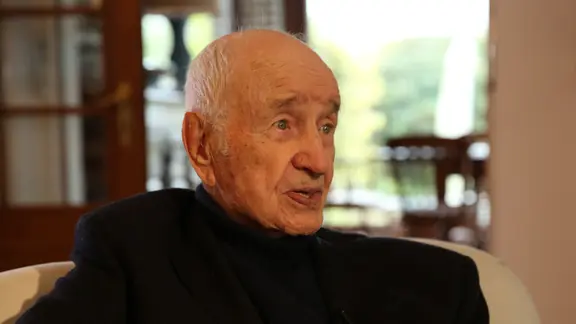 Armin Mueller-Stahl sitzt auf einem Sofa.