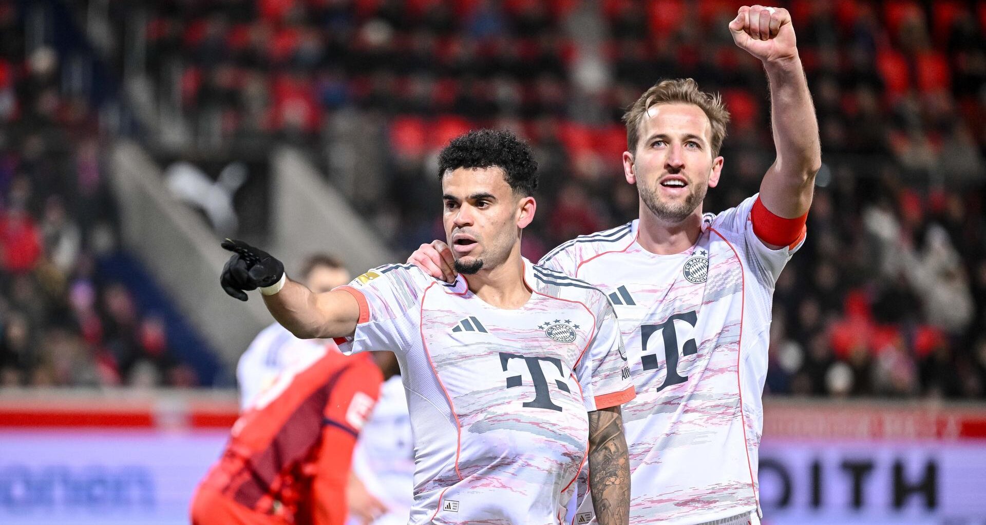 Das Bild zeigt zwei Fußballer, die sich seitlich umarmen und ihre beiden freien Hände zum Torjubel hochrecken.