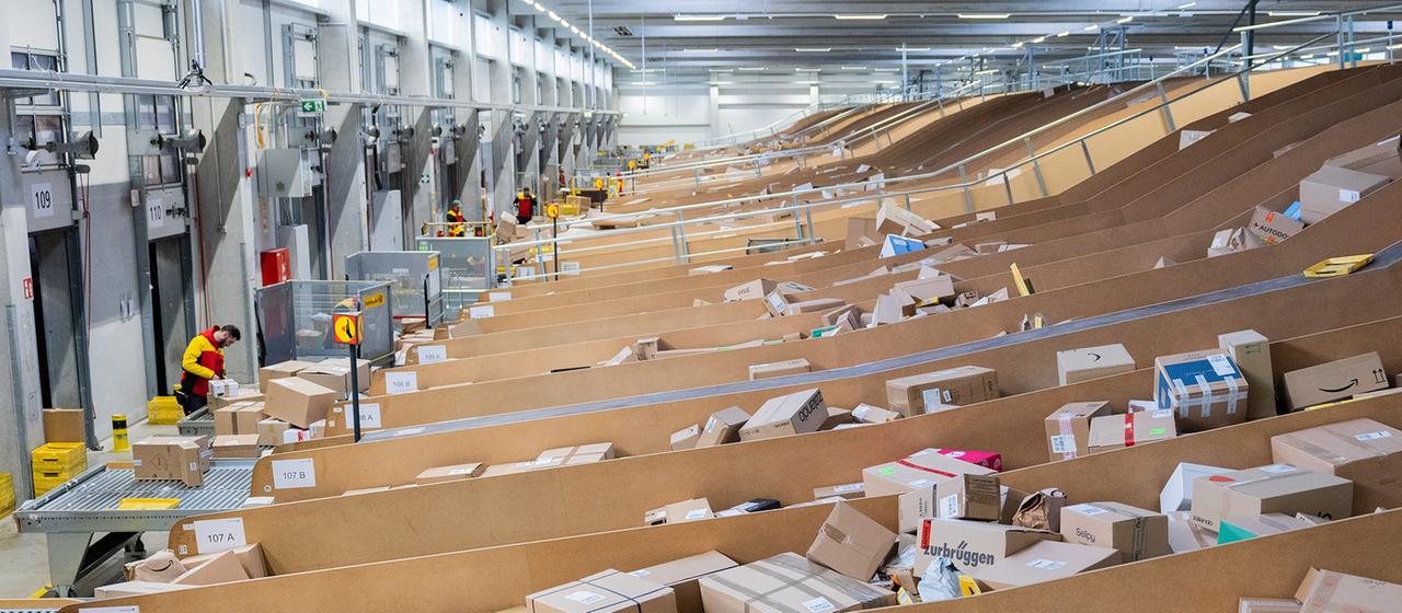 Paketzusteller sortieren und räumen in einer Zustellbasis von Deutsche Post DHL Pakete in Zustellfahrzeuge.