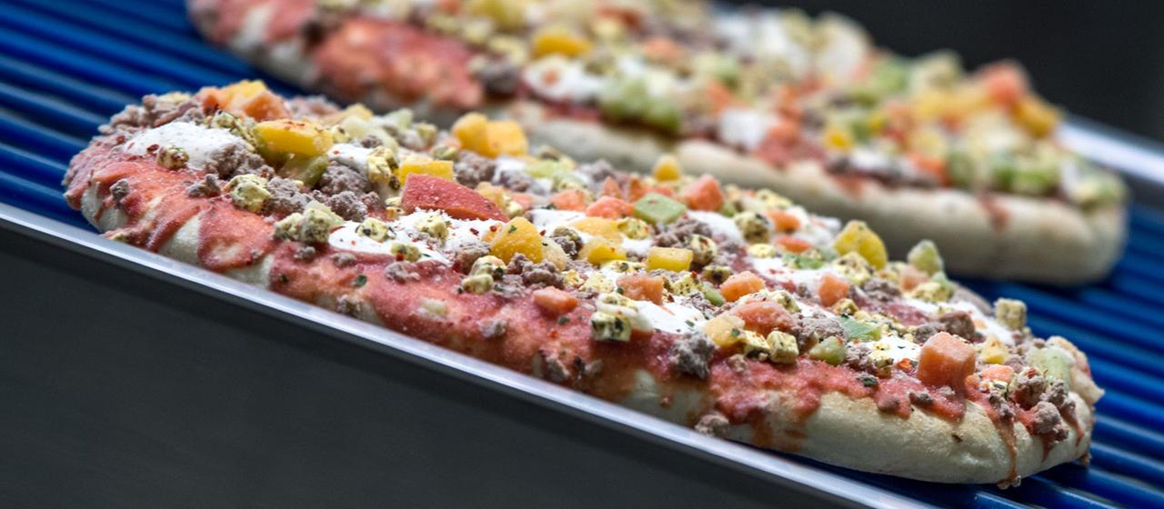 Tiefgefrorene Pizzen laufen über ein Transportband. | dpa Tiefgefrorene Pizzen laufen über ein Transportband.