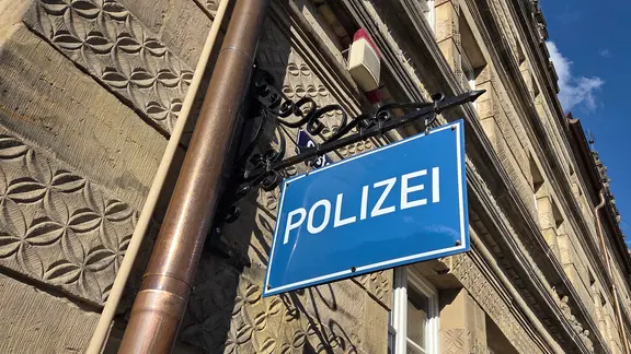 Auf einem blauen Schild das Wort "Polizei".