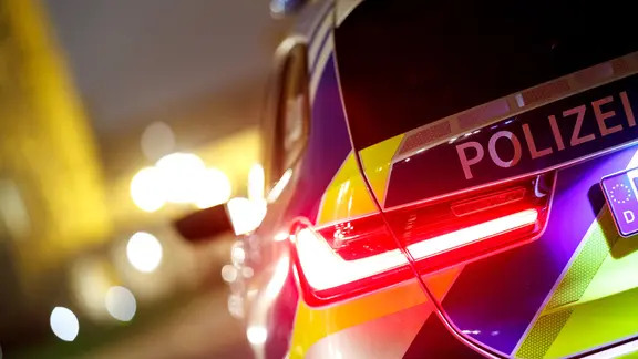 Ein Einsatzfahrzeug der Polizei in der Dämmerung mit leuchtenden Lichtern.