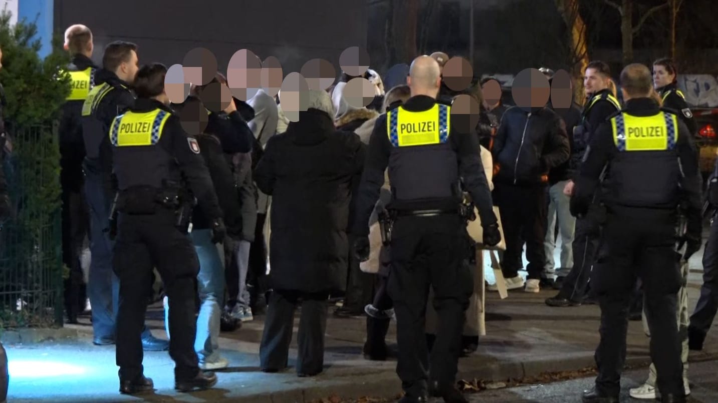 Polizisten stehen vor einer großen Gruppe: Bei einer Trauerfeier in Steilshoop ist ein Streit zwischen den Gästen eskaliert. Polizisten stehen vor einer großen Gruppe: Bei einer Trauerfeier in Steilshoop ist ein Streit zwischen den Gästen eskaliert.