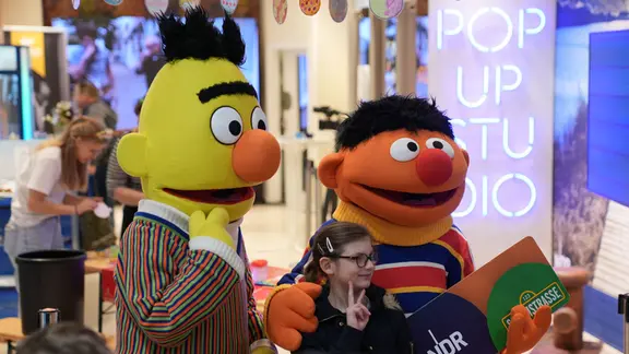 Ernie und Bert posieren mit einem jungen Mädchen beim NDR-POP-UP-Studio in Neumünster.