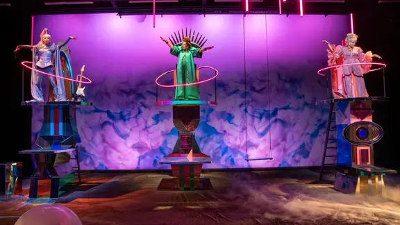 Drei Frauen auf einer Bühne auf Podesten wie Göttinnen inszeniert