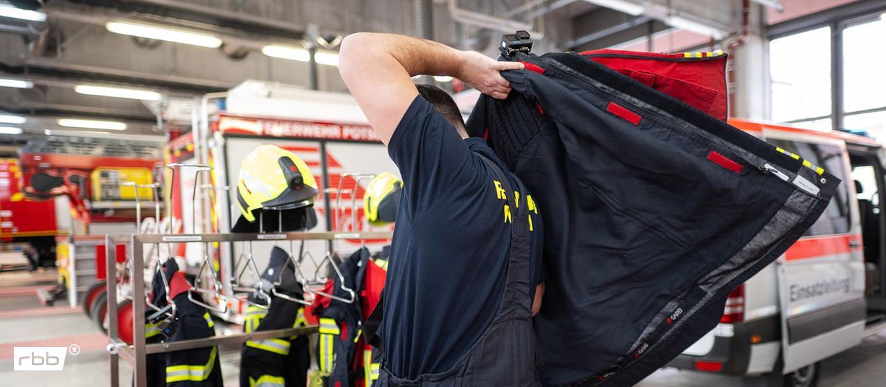 Symbolbild: Ein Feuerwehrmann zieht sich während der Vorstellung zur Bilanz von Feuerwehr und Rettungsdienst Potsdam für einen Einsatz an. (Quelle: dpa/Gollnow)