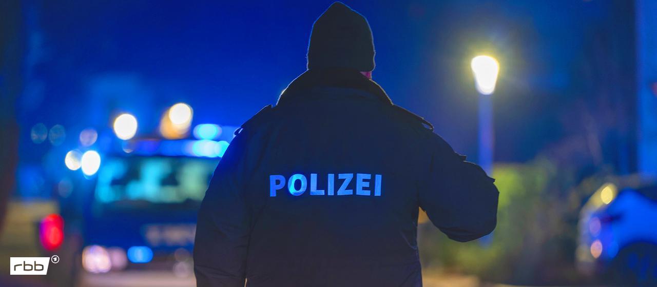 Symbolbild: Ein Polizist steht bei einem Einsatz vor mehreren Polizeifahrzeugen auf der Straße. (Quelle: dpa/Feil)