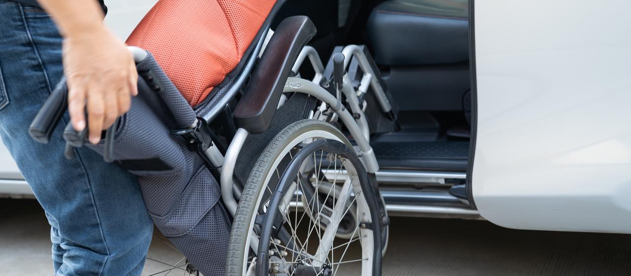 Eine Frau stellt einen Rollstuhl in ein Auto. | IMAGO/Panthermedia Eine Frau stellt einen Rollstuhl in ein Auto.