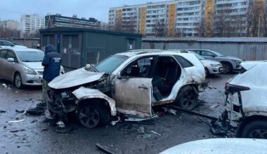 Ein Ermittler arbeitet am Tatort, an dem eine Bombe ein Auto zerstört hat.