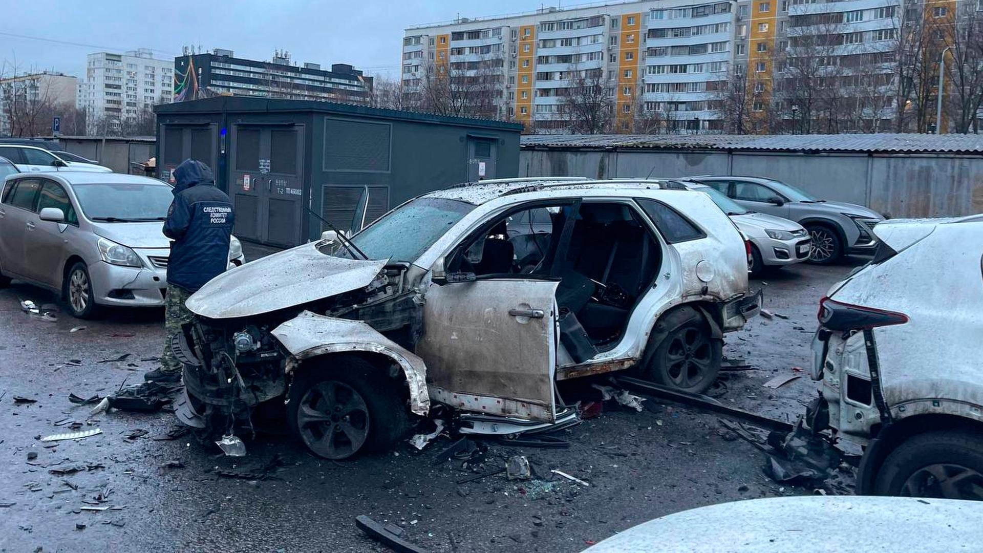 Ein Ermittler arbeitet am Tatort, an dem eine Bombe ein Auto zerstört hat. Ein Ermittler arbeitet am Tatort, an dem eine Bombe ein Auto zerstört hat.