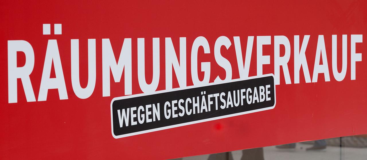 Ein Schild mit dem Hinweis "Räumungsverkauf wegen Geschäftsaufgabe" hängt an einem Geschäft.