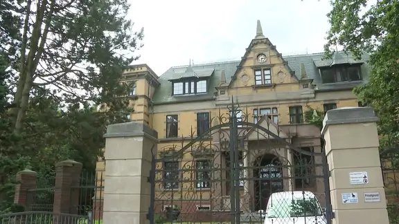 Das Bild zeigt eine Pforte und dahinter ein älteres Gutshaus in Jessenitz im Landkreis Ludwigslust-Parchim. | Screenshot Das Bild zeigt eine Pforte und dahinter ein älteres Gutshaus in Jessenitz im Landkreis Ludwigslust-Parchim.