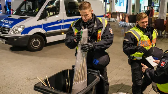 Polizisten entsorgen Raketen, die sie zuvor Passanten vor Betreten der Innenstadt von Hannover abgenommen haben.