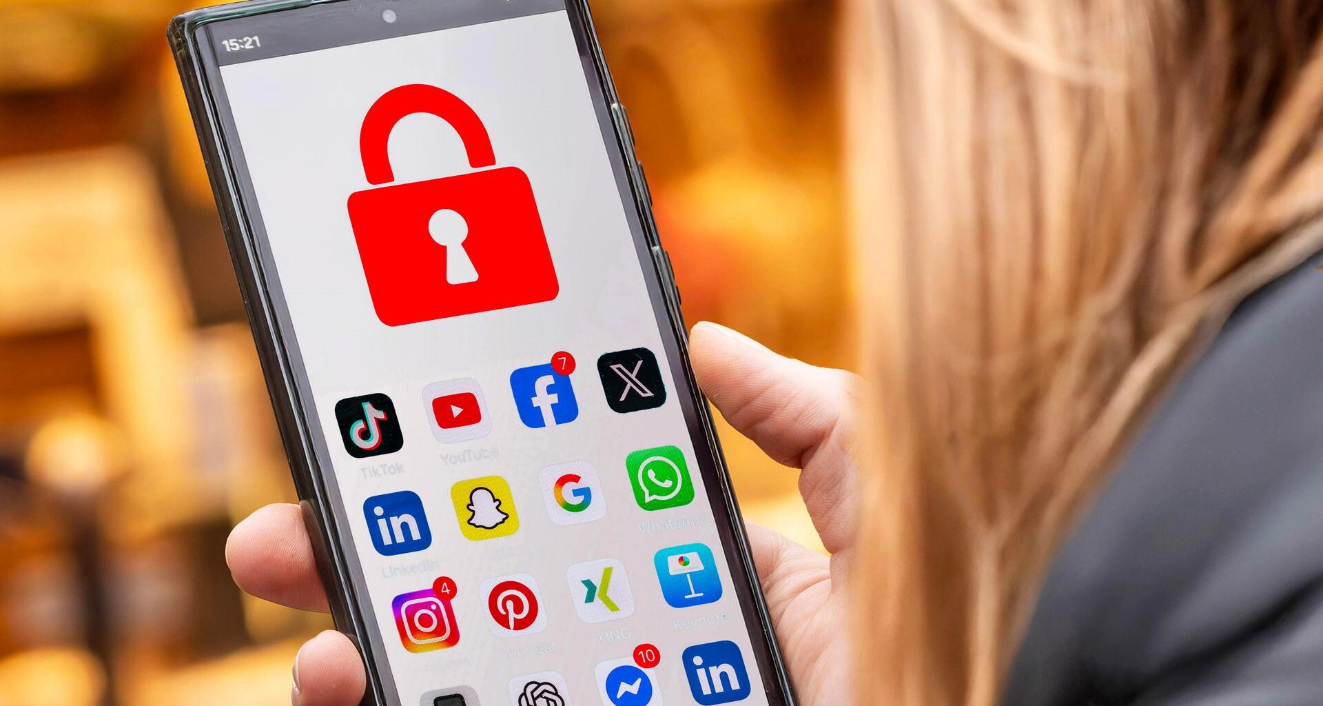 Symbolfoto: Schülerin mit Handy und Social Media Apps, die gesperrt sind