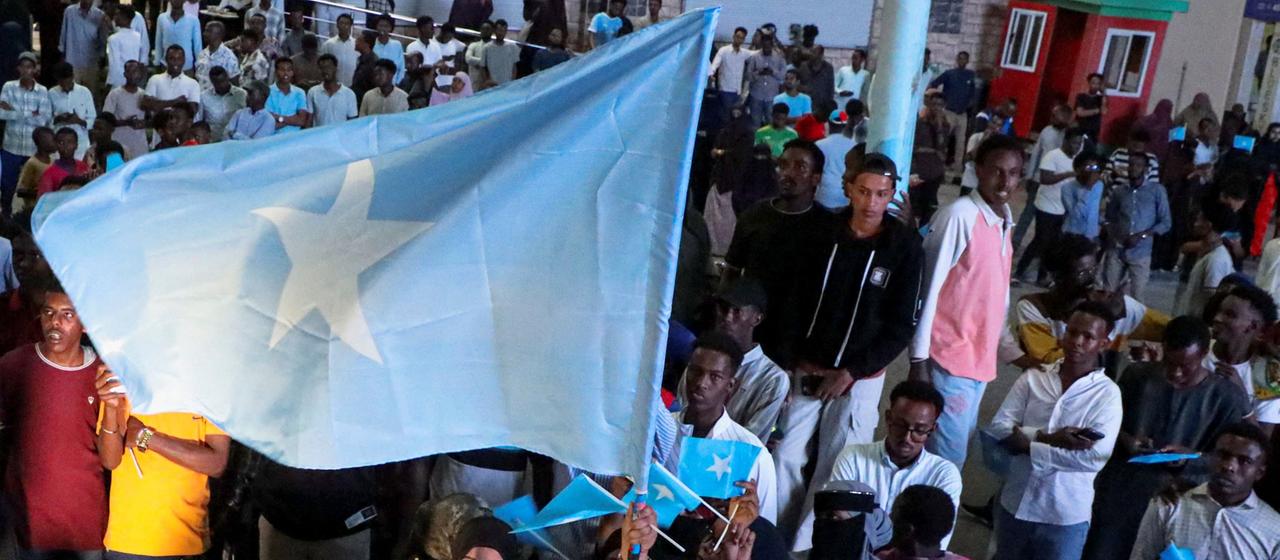 Eine Frau hält eine große somalische Flagge hoch.