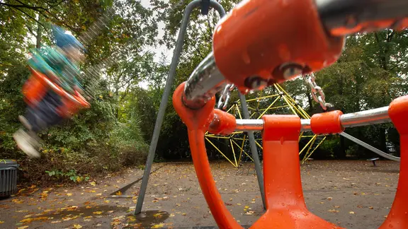 Ein Kind schaukelt auf einem Spielplatz.