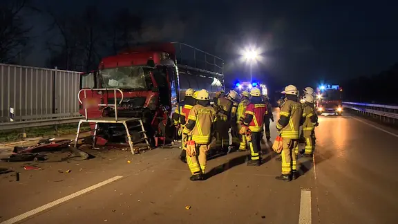 Feuerwehrleute stehen nach einem Unfall mit einem Lkw auf der A1.