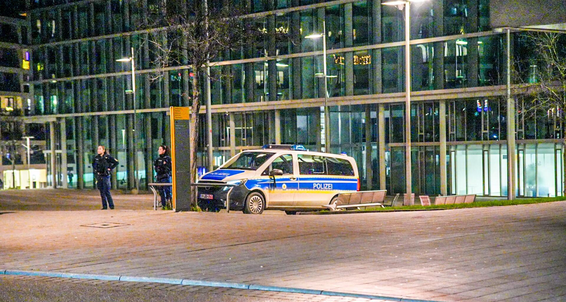 Ein Polizeifahrzeug steht am Stuttgarter Hauptbahnhof. Daneben stehen zwei Beamtinnen.