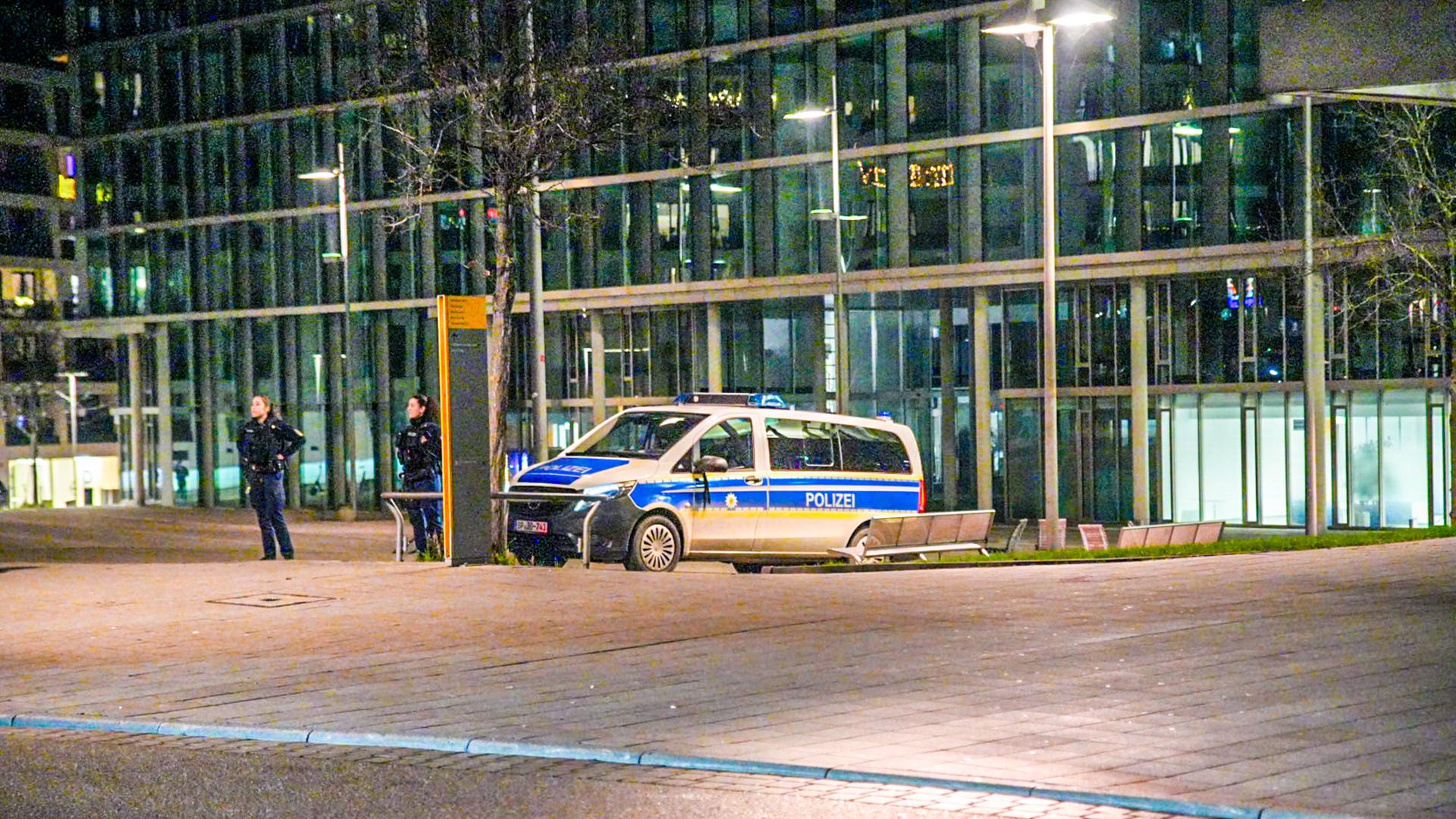 Ein Polizeifahrzeug steht am Stuttgarter Hauptbahnhof. Daneben stehen zwei Beamtinnen.