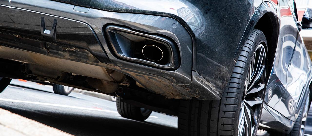 Der Auspuff eines dunklen SUVs.