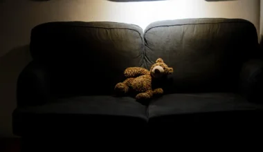 Symbolfoto zum Thema Kindesmissbrauch: Ein Teddy sitzt im Dunkeln allein auf einer Couch. Berlin, 25.03.2020.