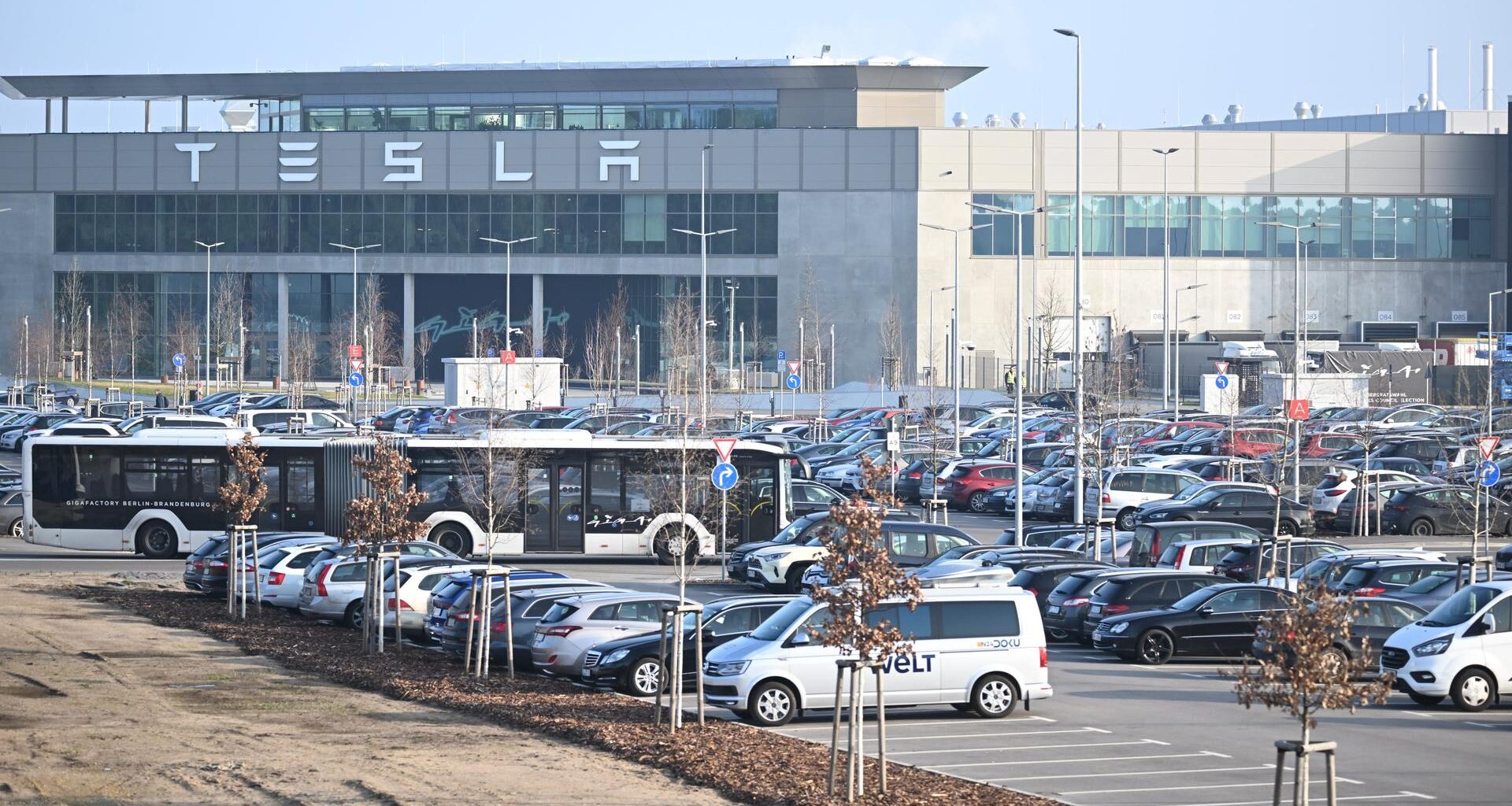 Grünheide: Die Morgensonne scheint auf den Eingang zum Tesla-Werk.