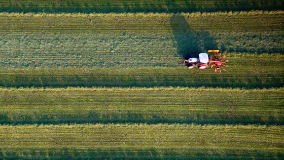 Zu sehen ist ein Acker aus der Vogelperspektive, über den ein Traktor fährt