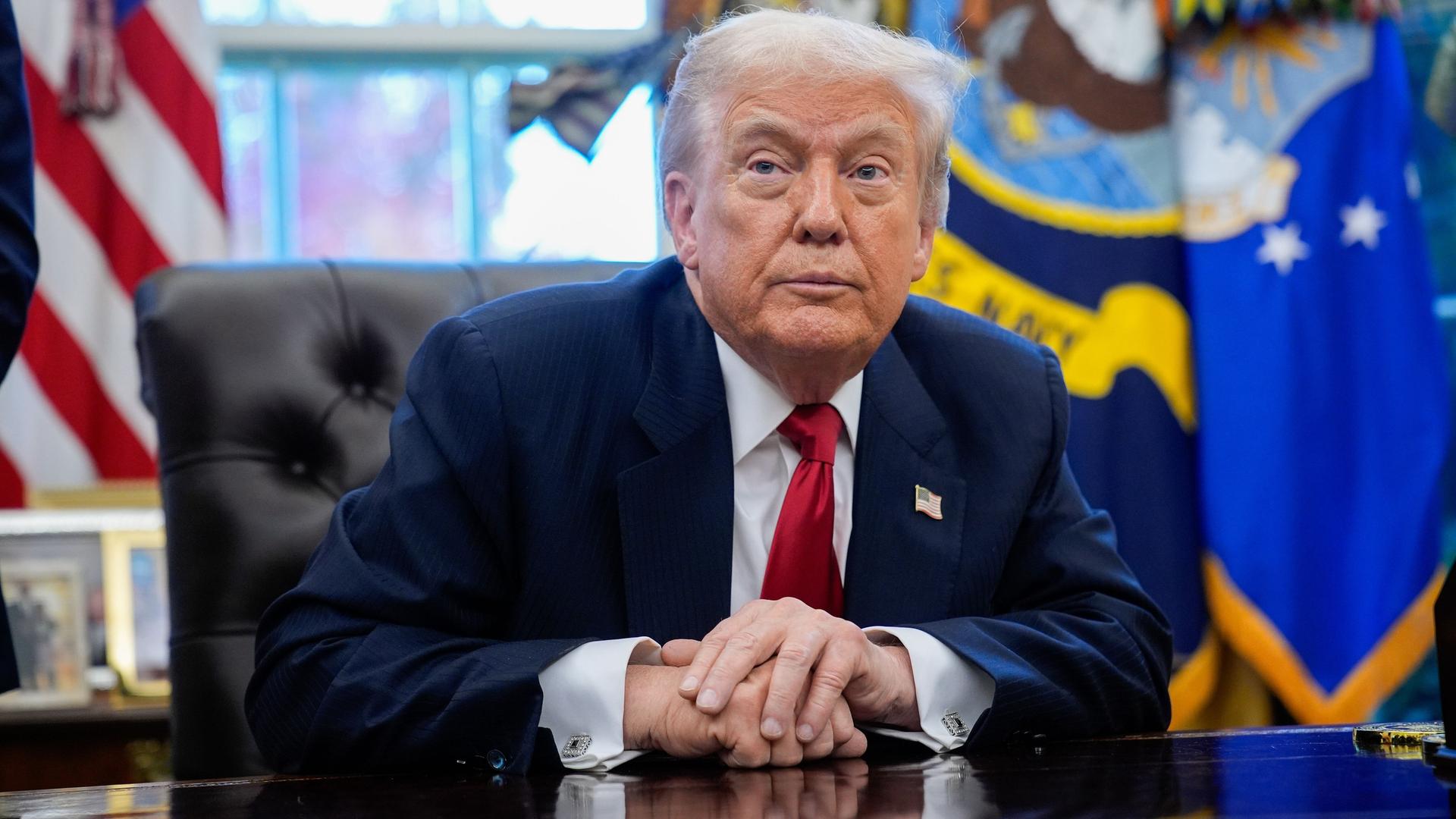 US-Präsident Trump sitzt an seinem Schreibtisch und blickt schräg an der Kamera vorbei. US-Präsident Trump sitzt an seinem Schreibtisch und blickt schräg an der Kamera vorbei.