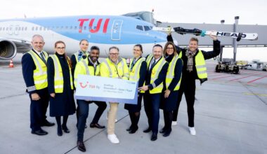 Mitarbeiter vom Flughafen Düsseldorf stehen vor einem Flieger von TUI. Sie halten ein Schild nach oben und tragen gelbe Warnwesten.