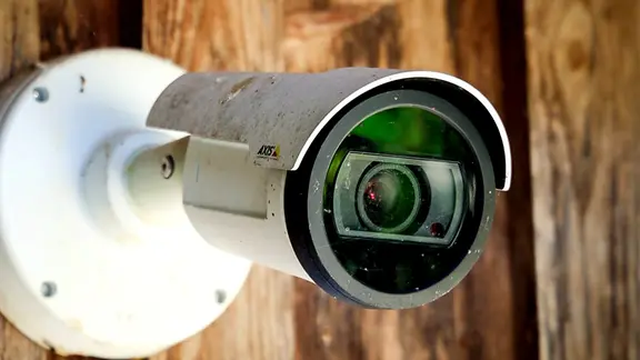 Eine private Überwachungskamera hängt an einer Holzwand.