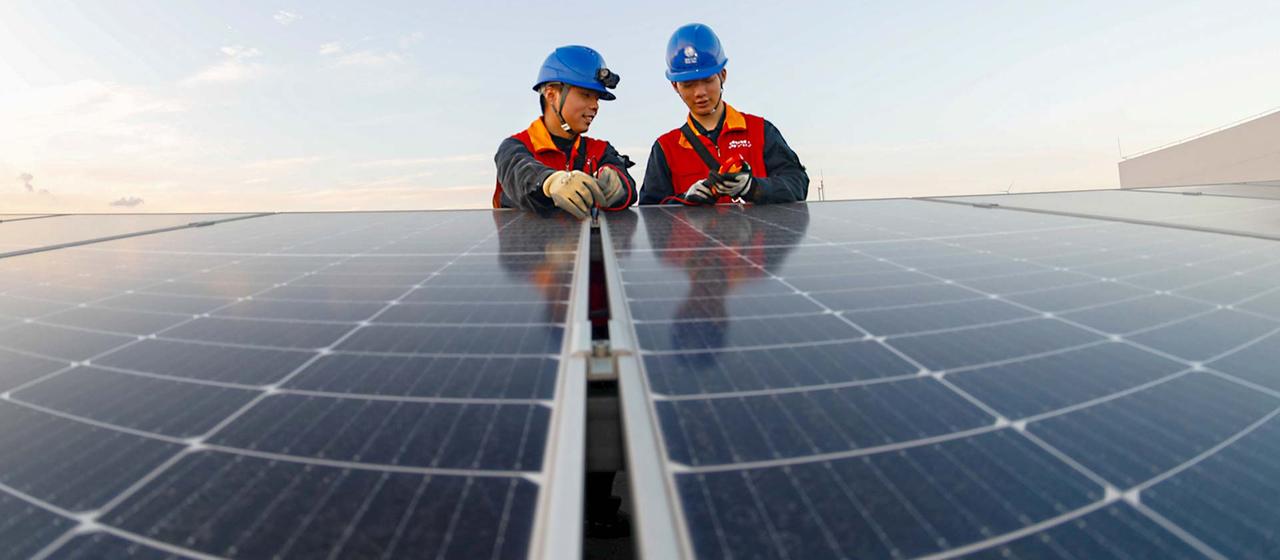 Chinesische Umwelttechniker an einer Solaranlage.