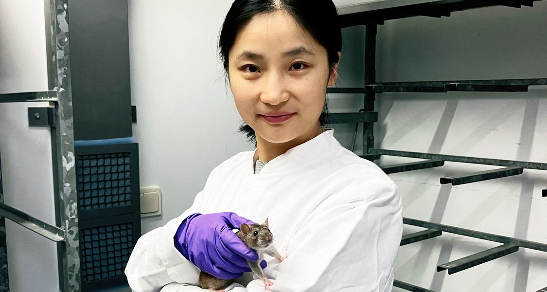 Forscherin mit einer Ratte im Arm