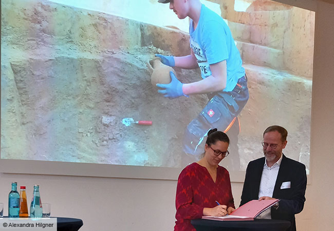 Elke Sichert von der Frankfurter Stadtarchäologie und Prof. Dirk Wicke unterzeichnen den Vertrag zur Aufnahme der Bodendenkmalpflege der Stadt Frankfurt in den Verbund. © Alexandra Hilgner