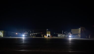 Auf einem Flugplatz stehen in der Nacht zwei spärlich beleuchtete Flugzeuge.
