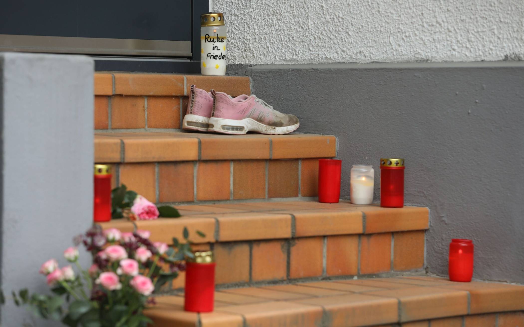 Blumen und Kerzen stehen im Mai vor der Wohnung in Troisdorf, in der eine 30-Jährige getötet wurde.