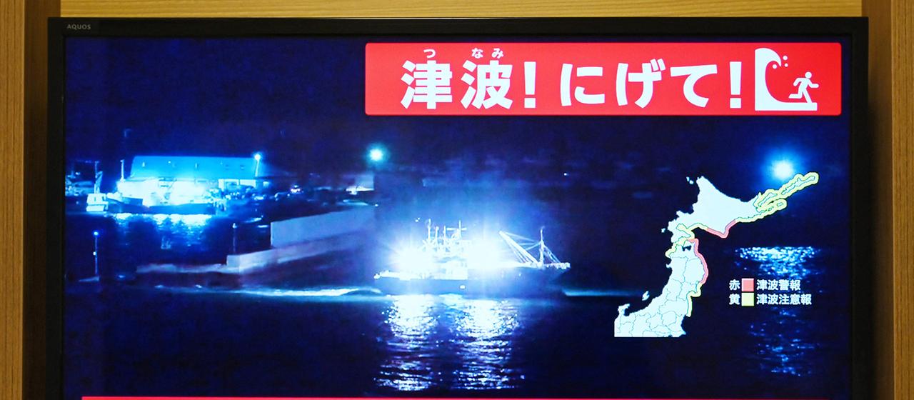 Eine Tsunami-Warnung wird auf einem Fernseher gezeigt.