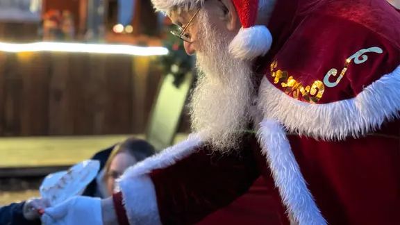 Kinder mit leuchtenden Augen und strahlenden Gesichtern: So erlebt Manfred Will Weihnachten auf dem Markt. | NDR, Vinetta Richter Ein Weihnachtsmann reicht einem Kind ein Geschenk.