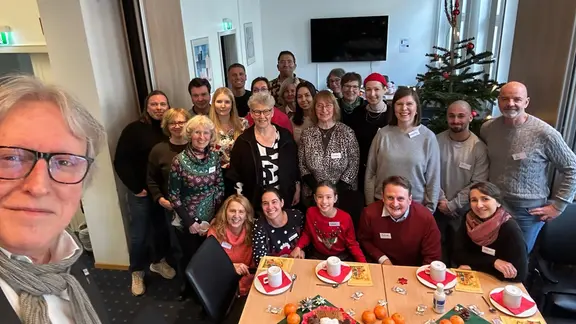 Eine Gruppe steht vor einem Weihnachtsbaum, in der Mitte ein 10-jähriges Mädchen.