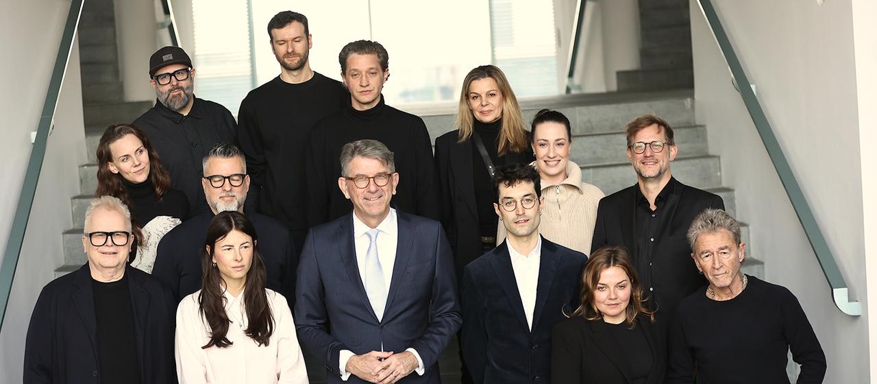 Wolfram Weimer steht mit Musikerinnen und Musikern zusammen auf einer Treppe. | EPA Wolfram Weimer steht mit Musikerinnen und Musikern zusammen auf einer Treppe.