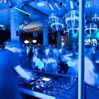 Dutzende Menschen tanzen in einem Club zur Musik.