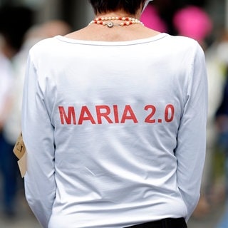 Eine Frau trägt ein T-Shirt mit der Aufschrift "Maria 2.0". (Foto: dpa Bildfunk, picture alliance / Geisler-Fotopress) Eine Frau trägt ein T-Shirt mit der Aufschrift "Maria 2.0".