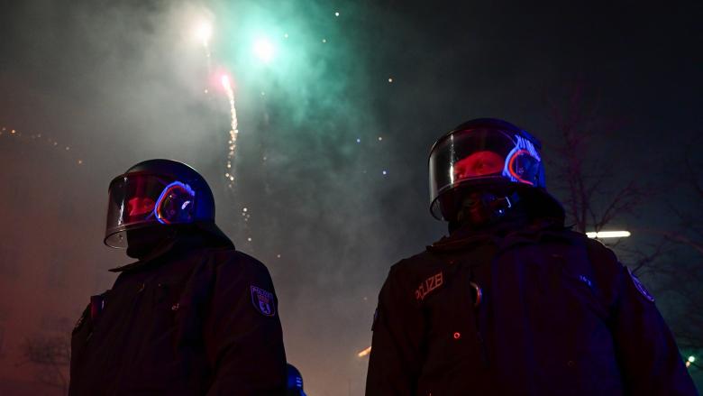 Feuerwerk explodiert während der Silvesternacht in Neukölln hinter Polizei. +++ dpa-Bildfunk +++