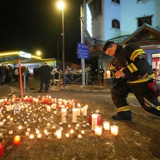 Menschen legen Kerzen und Blumen in der Nähe der Bar Le Constellation in Crans-Montana ab, in der ein verheerendes Feuer während der Neujahrsfeierlichkeiten Tote und Verletzte forderte.