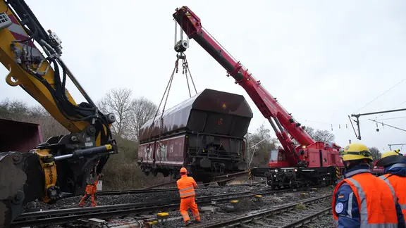 Ein entgleister Wagon wird mit einem Kran angehoben.