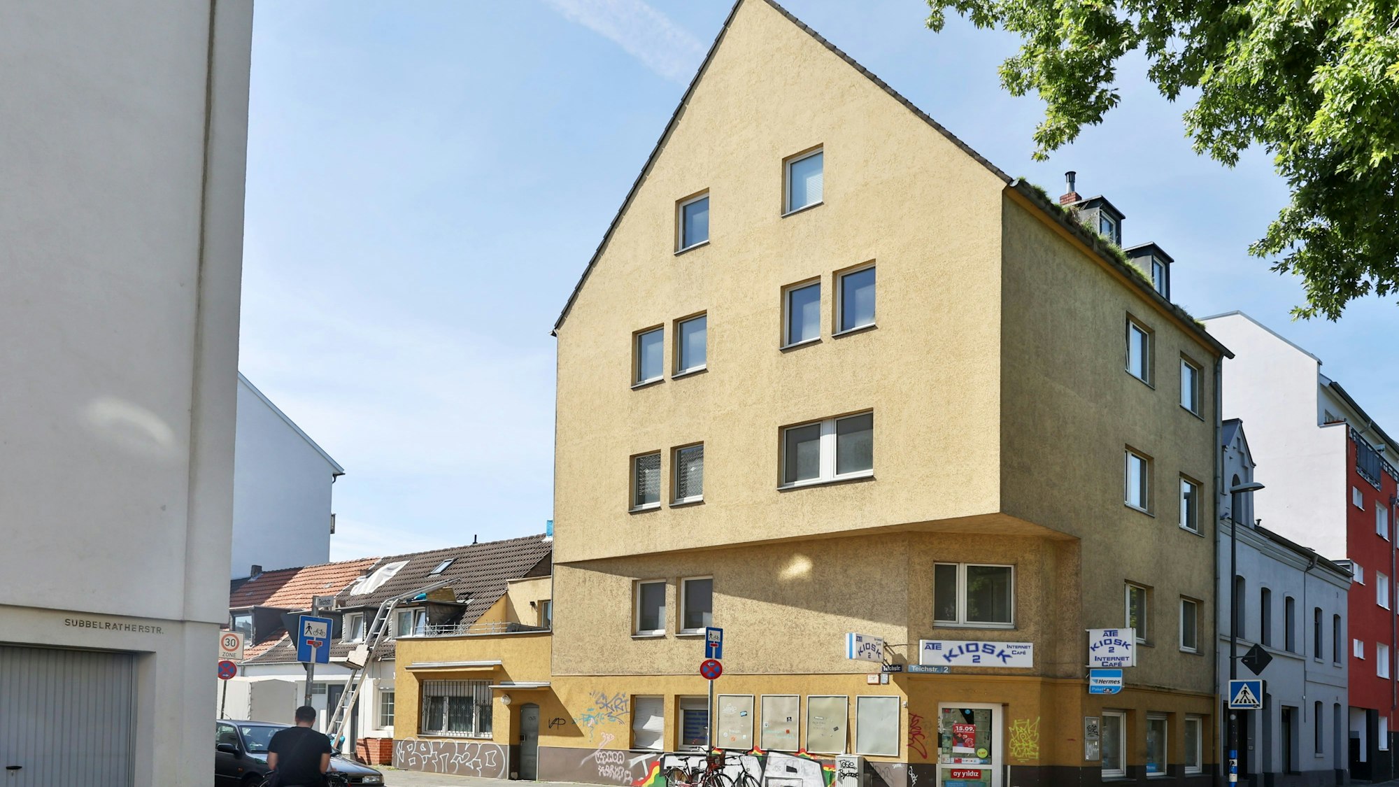 Ein großes Haus mit gelber Fassade an einer Straßenecke ist zu sehen.