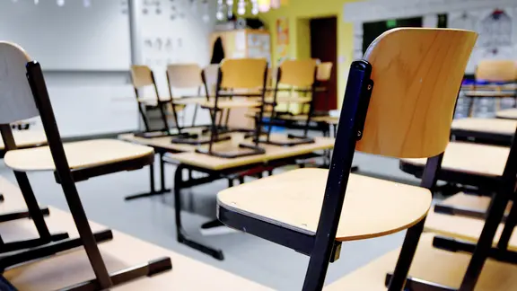 Ein leeres Klassenzimmer in einer Schule. Stühle hochgestellt auf Tischen.