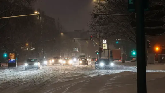 Langsam fahren Autos und Fahrzeuge bei Schneefall über eine Straße