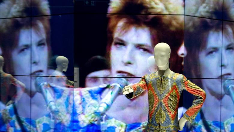 Ein sich spiegelnder Film zeigt am 18.05.2014 im Martin-Gropius-Bau in Berlin während der Vorbesichtigung der Ausstellung "David Bowie" einen Auftritt Bowies bei der BBC im Jahr 1972 (Quelle: dpa/Soeren Stache)