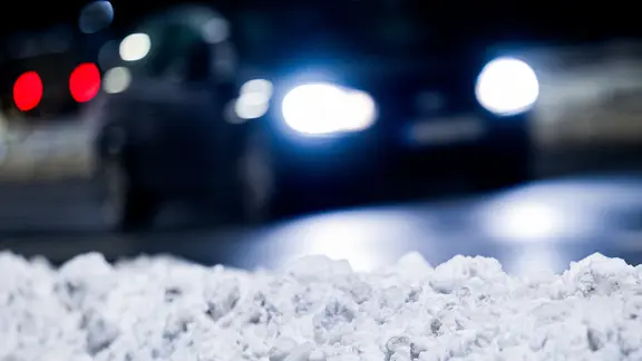 Ein Auto fährt vorbei an geräumtem Schnee.