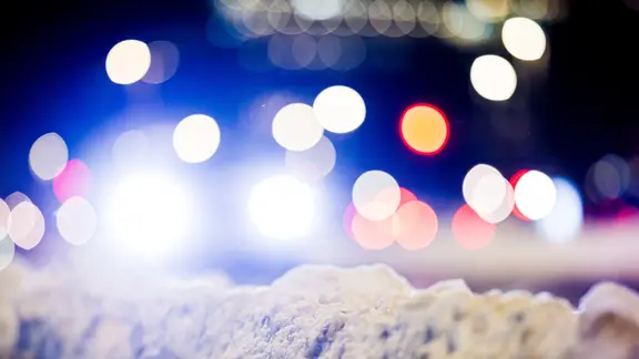 Autos fahren am frühen Morgen eine Straße im Zentrum von Hannover entlang, während Schnee den Fahrbahnrand säumt.